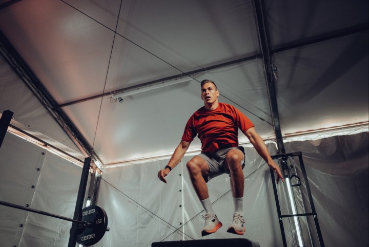 Athlete jumping onto a box in a weight room under a tent roof