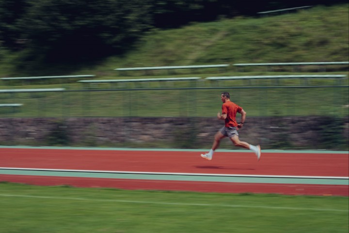 Runner in a red shirt on the track, shot from the side with motion blur