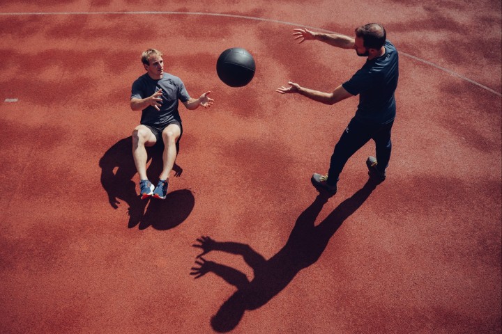 Athlete and coach passing a medicine ball on the track, photographed from above