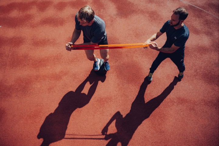 Coach and athlete working with a resistance band on the track, shot from above